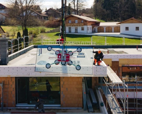 Mit dem Kran werden die großen Glasscheiben für die große Glasfront eines Neubaus in Hanglage zur Montage gehoben.