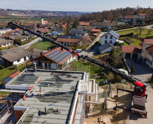 Mit dem Kran werden die großen Glasscheiben für die große Glasfront eines Neubaus in Hanglage zur Montage gehoben.