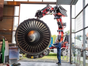 Die Flugzeugturbine wird mit dem Kran im Museum platziert. Herausforderung war hier unter anderem die empfindliche Glasarchitektur des Gebäudes.